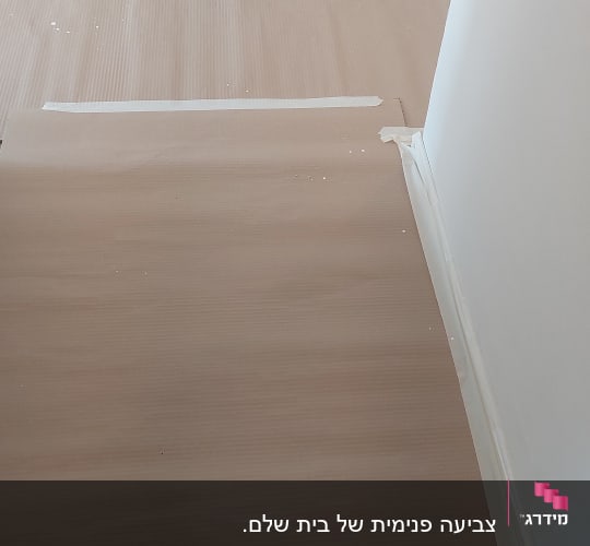 הגנה וכיסוי רצפה בקרטון גלי וסרט מדבק כהכנה לצביעת קירות